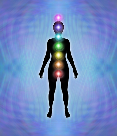 A neat stack of seven rainbow coloured chakra vortexes against a female silhouette on a purple blue matrix wave background with copy space