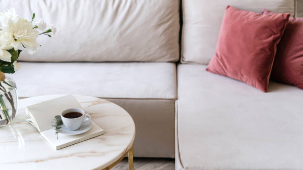 istock Selective focus on marble coffee table with cup and diary next to beige couch 1901873430