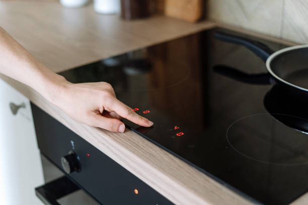 istock Selective focus on woman hand pressing on digital control panel of induction cooker in kitchen 1901873962