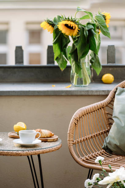 istock Selective focus on table with cup and rattan chair on terrace with flowers 1901875519