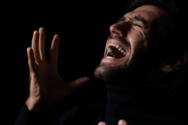 istock Sadness Young hopeless man screaming and shouting Frustrated handsome man agonizing and torturing expression He get maddening and overwhelming rage in the dark room black background Aggressive man 1901876167