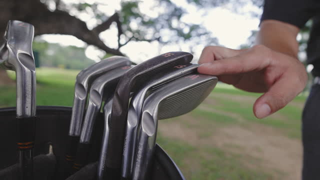 Golf player choosing golf clubs from the leather bag