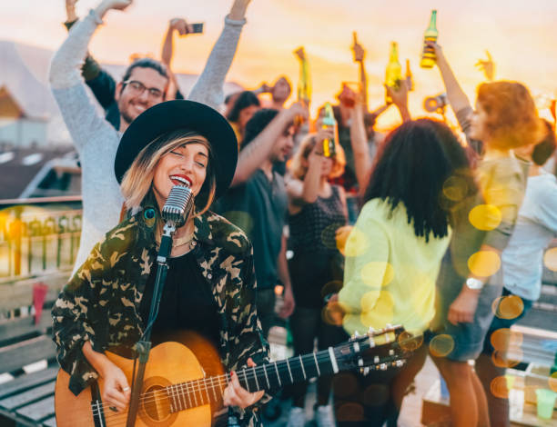 friends enjoying a guitar performance on the rooftop - individual event women people autumn imagens e fotografias de stock