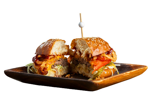 Half part of burger on the wooden plate. A burger cut in half with a meat patty isolated on a white background. The concept of unhealthy and delicious fast food.