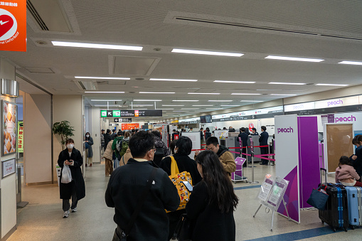 Long lines at Nagasaki airport in Nagasaki prefecture Japan. Passengers wait, as updates from Haneda airport are announced.