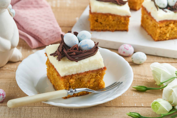 istock Easter carrot cake bars decorated with chocolate nest and chocolate candy eggs blossoming cherry or apple flowers on rustic light wooden backgrounds. Easter holiday meal. Traditional Easter food. 1901984962