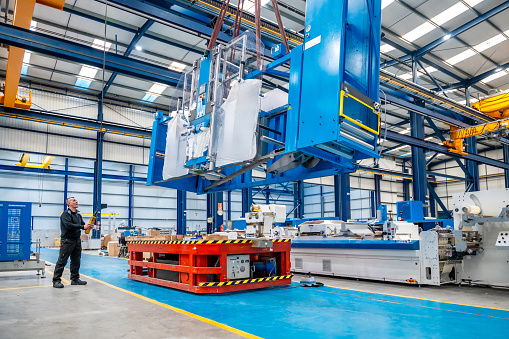 Horizontal photo with copy space of a crane lifting very heavy machinery in a factory