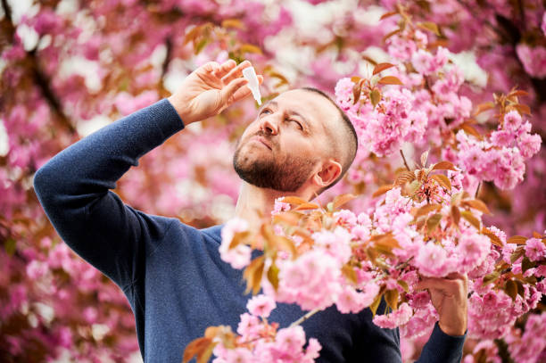 istock Man allergic using medical eye drop, suffering from seasonal allergy at spring in blossoming garden 1902025447