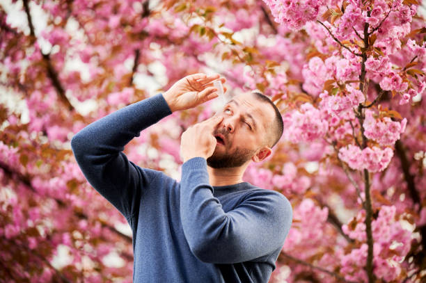 istock Man allergic using medical eye drop, suffering from seasonal allergy at spring in blossoming garden 1902025448