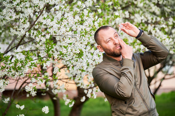 istock Man allergic using medical eye drop, suffering from seasonal allergy at spring in blossoming garden 1902025992