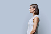 Profile view, confident young business woman, copy space gray studio background