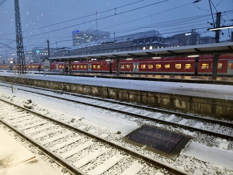 München Hauptbahnhof or Munich Central Station is the main railway station in the city of Munich, Germany. München Hauptbahnhof sees about 450,000 passengers a day. The image shows a regioinal train with a platform during heavy snowing.