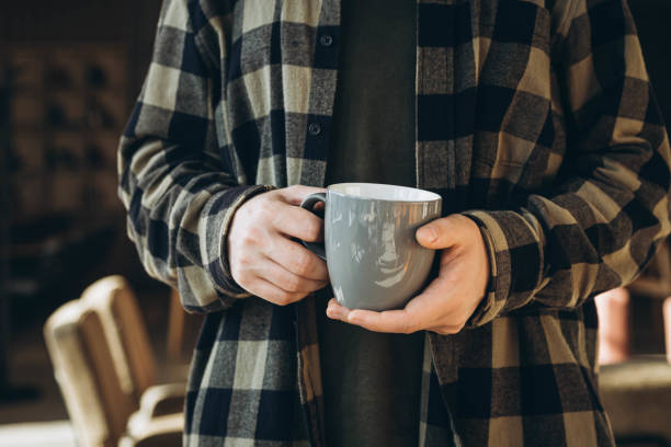 istock A man drinks tea or coffee in a modern cozy cafe. Cup in male hands close-up. 1902041060