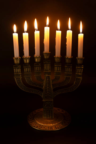 istock Menorah with the word JERUSALEM written on its base with 7 lit candles isolated on a dark background 1902059848