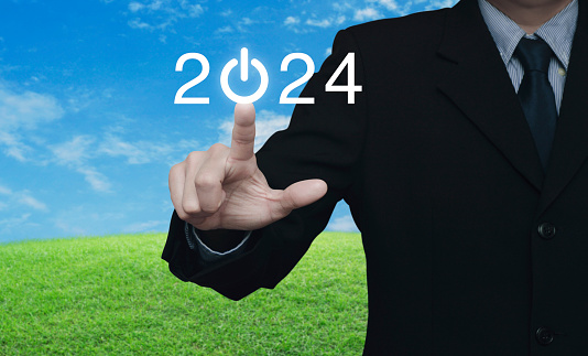Businessman pressing 2024 start up business flat icon over green grass field with blue sky, Business happy new year 2024 success concept