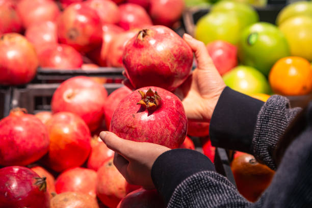 istock A woman chooses pomegranate fruit at a grocery store. 1902069001