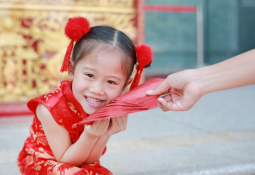 Happy little Asian girl received a red envelope. Chinese New Year celebration.