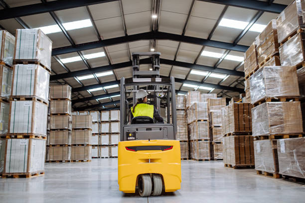 istock Female warehouse worker driving forklift. Warehouse worker pricking, preparing products for shipmennt, delivery, checking stock in warehouse. 1902088054