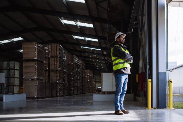 istock Portrait of warehouse worker taking break from work, standing and looking outdoors. Worker in reflective clothes, with copy space. 1902097118
