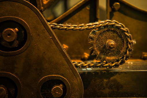Metal chain of a chain drive with a gear of an old production machine in a factory from the last century