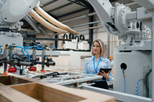 istock Female engineer in modern industrial factory, checking robotic arm, controling process and manufacturing equipment or machinery. Manufacturing facility with robotics and automation. 1902105399