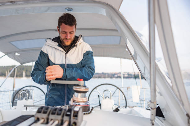 istock Young Sailor Winding Rope Manually With Winch On Sailboat 1902109592