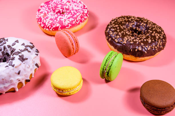 istock Fresh glazed donuts and french macaroons isolated on a pink background 1902116267
