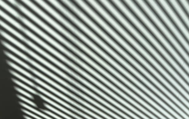 Shadows on wall. Abstract light, black shadow overlay from window shade on mint green wall. Sunlight shadow background