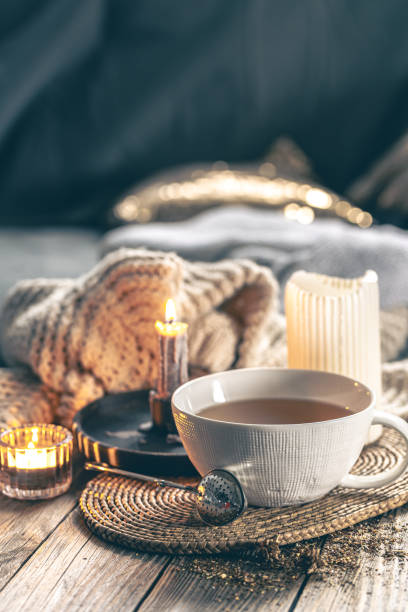 istock Cozy home composition with a cup of tea, candles and a knitted element. 1902156679