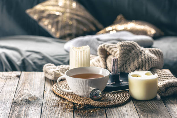 istock Cozy home composition with a cup of tea, candles and a knitted element. 1902157192