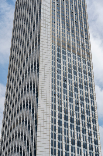 Close-up on a tall city office building with cloudy sky beyond.