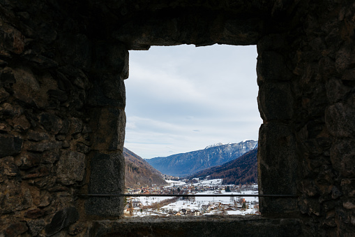 view on snowy mountains and the valley from the window in the old stone wall
