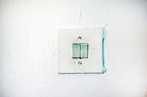 An old light switch on the wall. Electrical switching. Painted switch.