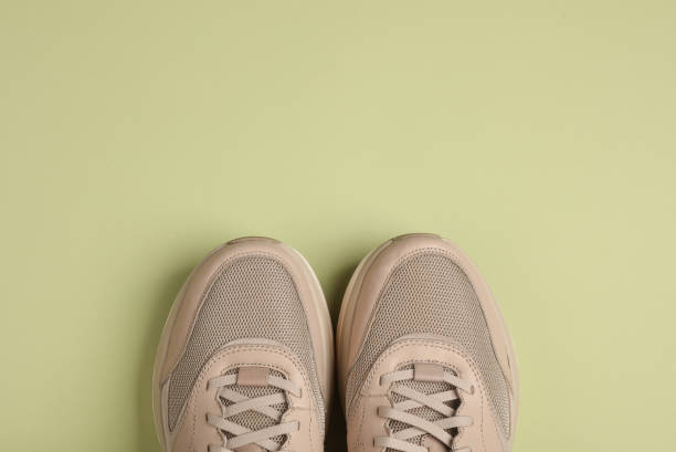 istock Beige running shoes on a green background. Top view 1902240551