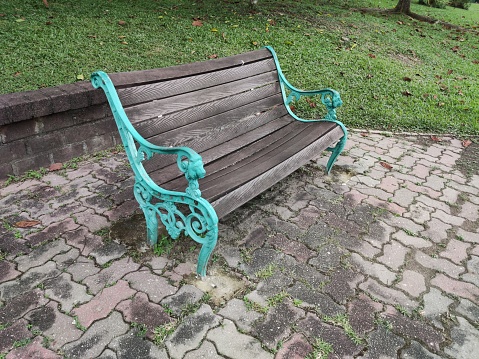 Queenstown, Singapore - December 24, 2023.\nThe city garden chair, crafted from water- and sun-resistant wood, adds a touch of beauty to the roadside, offering a scenic view of the grass and greenery.