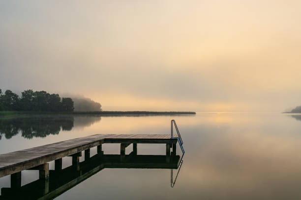 istock Bathing jetty at the lake Schaalsee during sunrise in Seedorf, Germany 1902273837