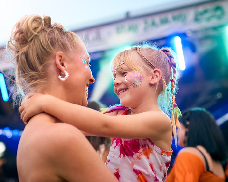 Mother With Daughter Wearing Glitter Having Fun At Outdoor Summer Music Festival