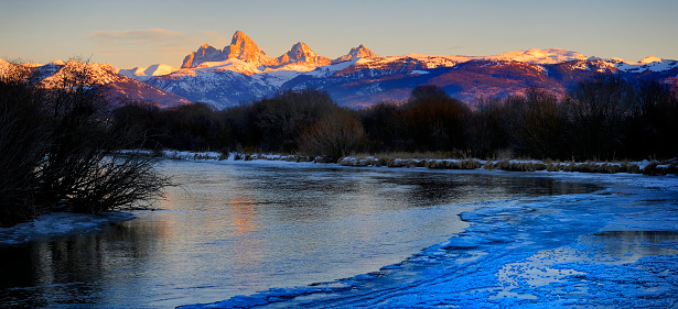 Grand Tetons reflected in still water of the Snake River at Oxbow Bend.