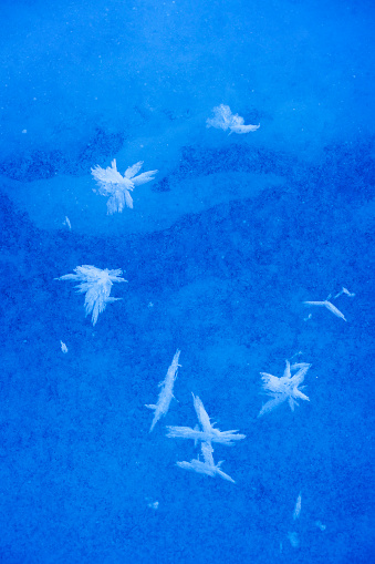 Ice crystals and forms on frozen river water in wilderness patters of nature