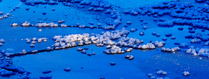 Ice crystals and forms on frozen river water in wilderness patters of nature