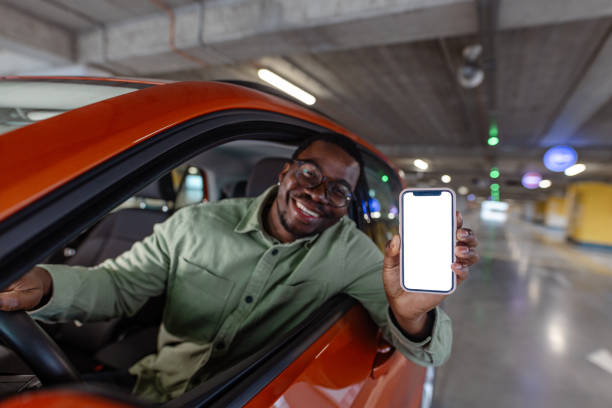 istock Young man renting a car with a mobile app on smart phone. Blank Screen. Copy Space. 1902322421