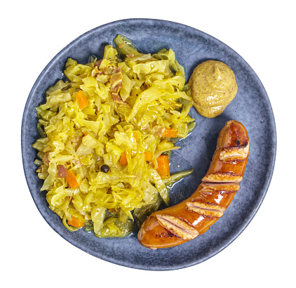 Braised cabbage with wiener and mustard on a blue plate shot from above, isolated