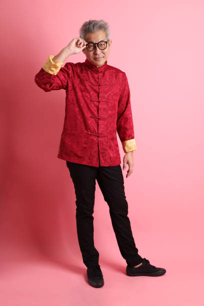 Happy Chinese new year. Asian Chinese energetic senior man wearing red traditional cheongsam qipao or changshan dress with gesture of Serious expression isolated on pink background.