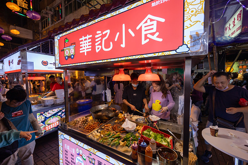 Hong Kong - December 31, 2023 : Street vendors cook food on their roadside stalls at Temple Street Night Market in Hong Kong.