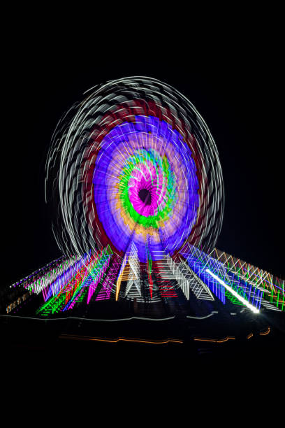 istock Intentional camera movement, slow shutter Zoom blur image of giant Ferris wheel illuminated and spinning at night in a funfair. 1902346586