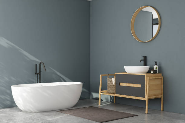 istock Modern minimalist bathroom interior, modern bathroom cabinet, white sink, wooden vanity, interior plants, bathroom accessories, bathtub and shower, white and blue walls, concrete floor. 1902375826