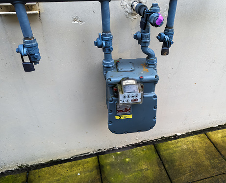 Portland, Oregon, USA - 12.28.2023: An outdoor gas meter is attached to the wall of a house.