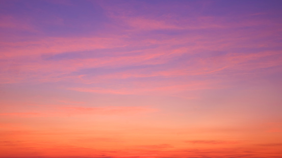 Sunset sky background with beautiful pink sunset clouds on colorful yellow, orange and blue purple sunlight on romantic evening twilight sky