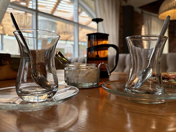 female hand pours hot tea into a glass turkish cup in a cafe. morning breakfast - tulipe cup стоковые фото и изображения