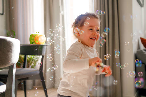 istock Happy little girl is playing with soap bubbles 1902428774